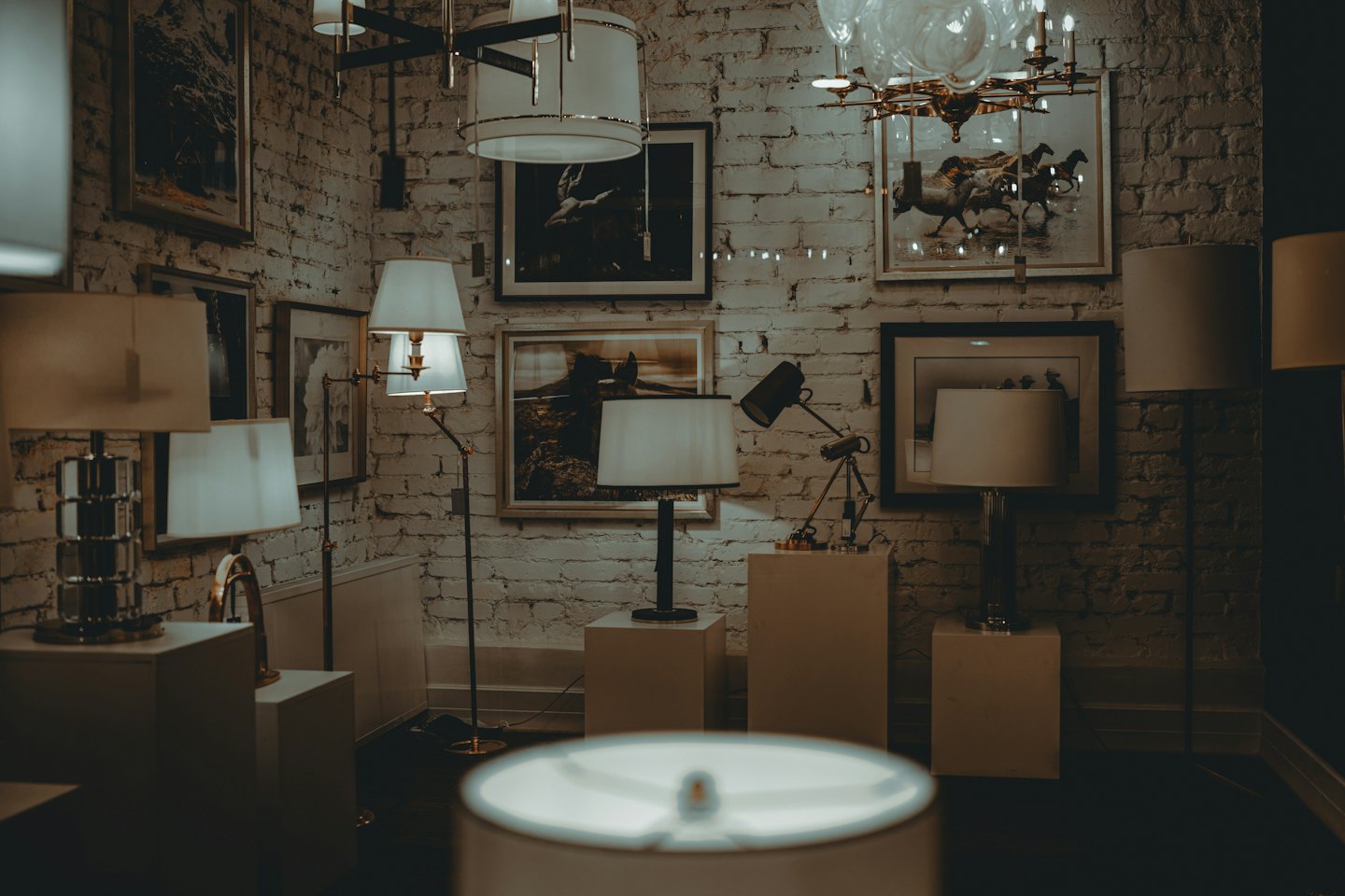Lampade illuminate e quadri incorniciati decorano uno spazio espositivo.